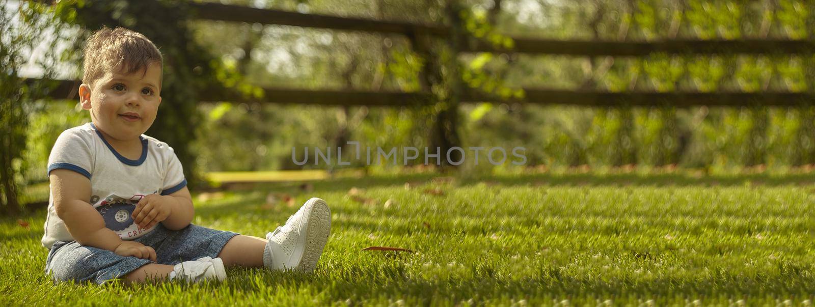 Cute Child sitted on the grass, banner with copy space