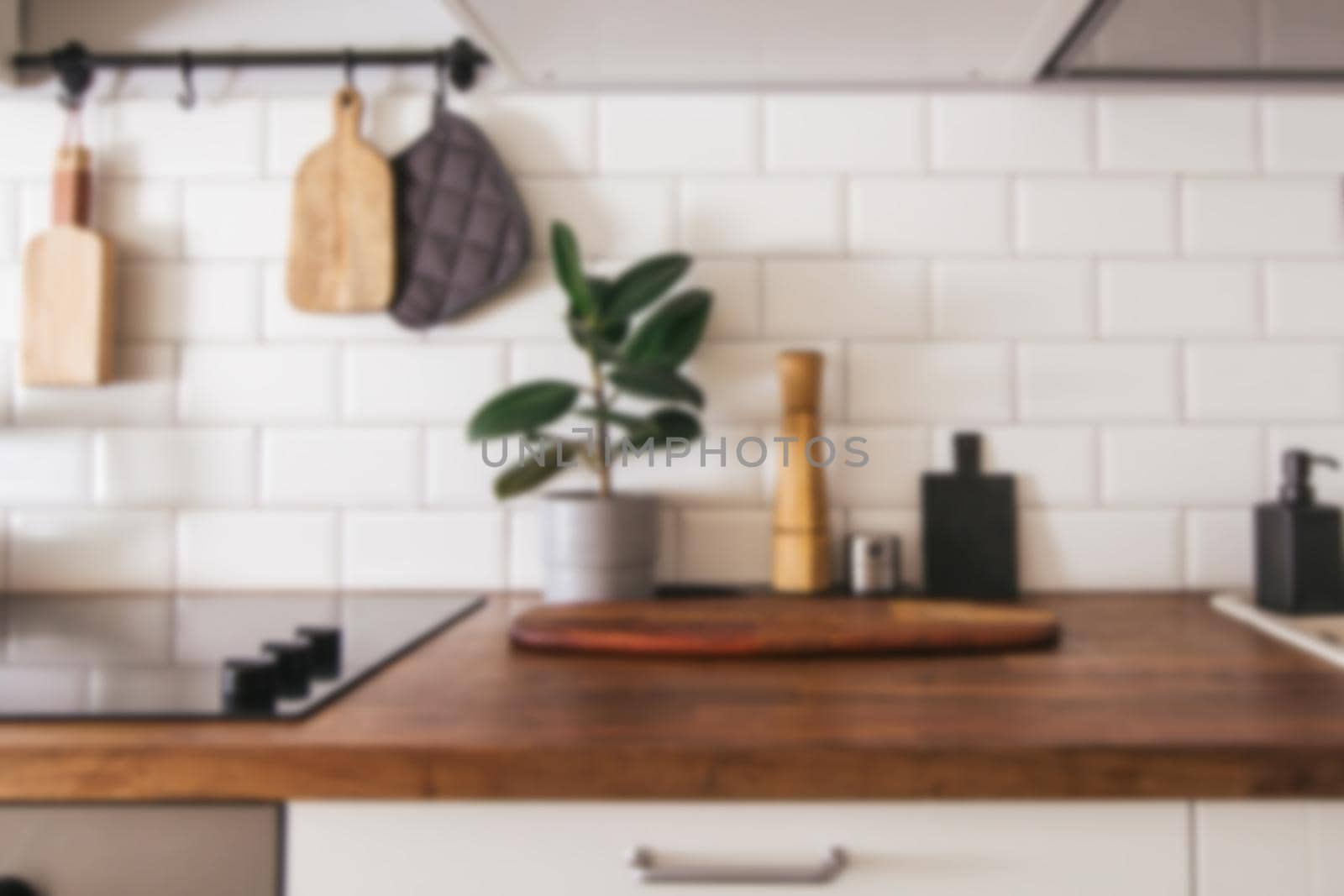 Kitchen brass utensils, chef accessories - blurred kitchen background . Hanging kitchen with white tiles wall and wood tabletop.Green plant on kitchen background side view