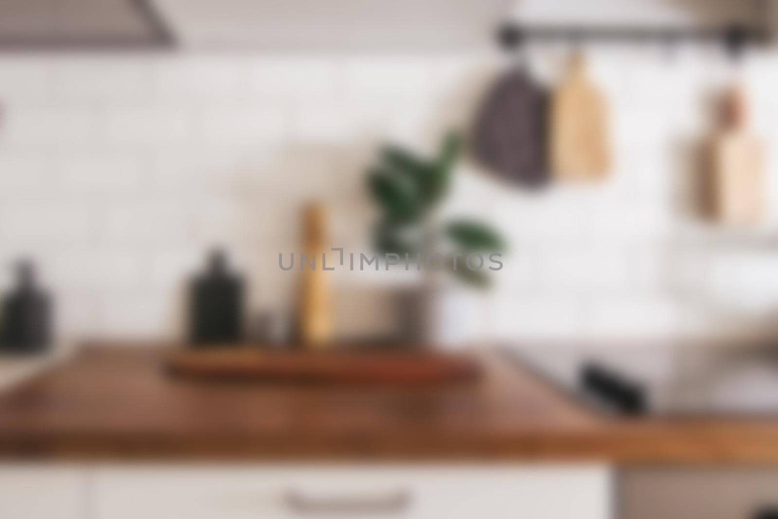 Kitchen brass utensils, chef accessories - blurred kitchen background . Hanging kitchen with white tiles wall and wood tabletop.Green plant on kitchen background by katrinaera