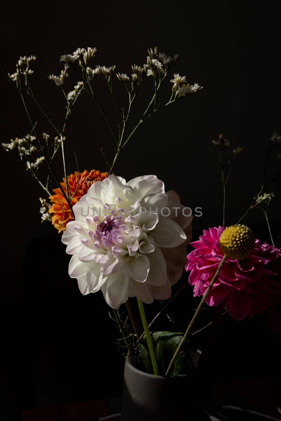 Beautiful orange coloured sunny Dahlia flower , yellow craspedia and white dried flowers, modern bouquet flowers dark style still life side view