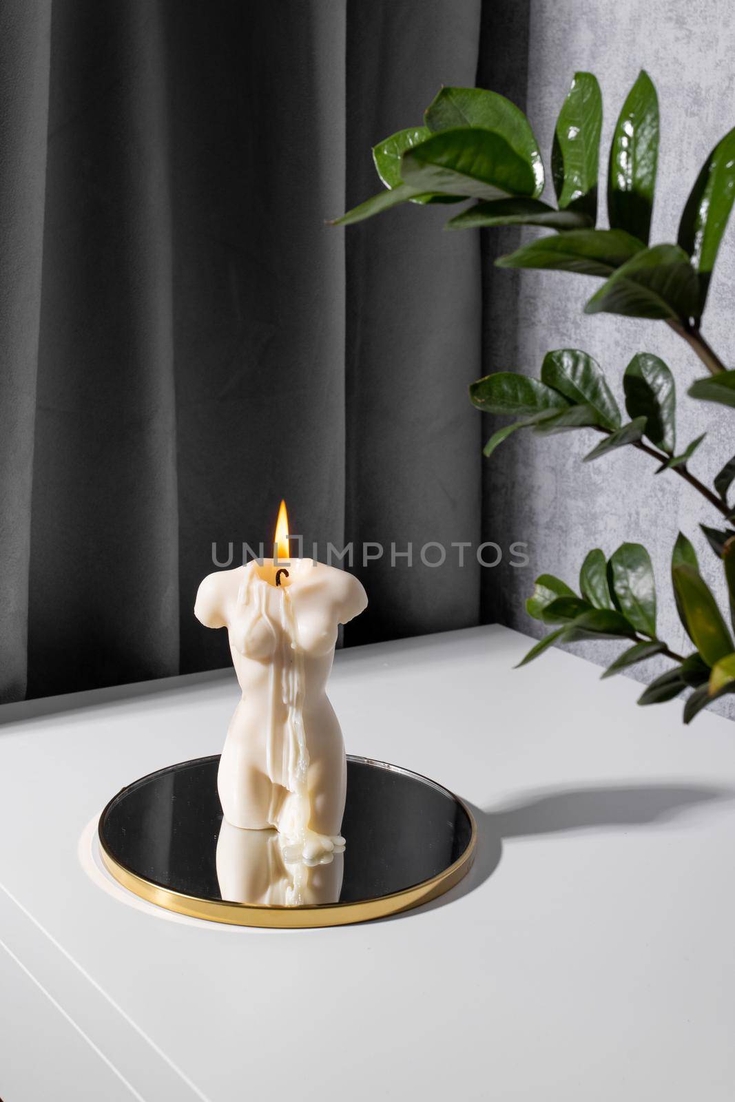 Candle in woman torso shape burning in grey interior in slow motion, atmosphere and smoke after candle vertical