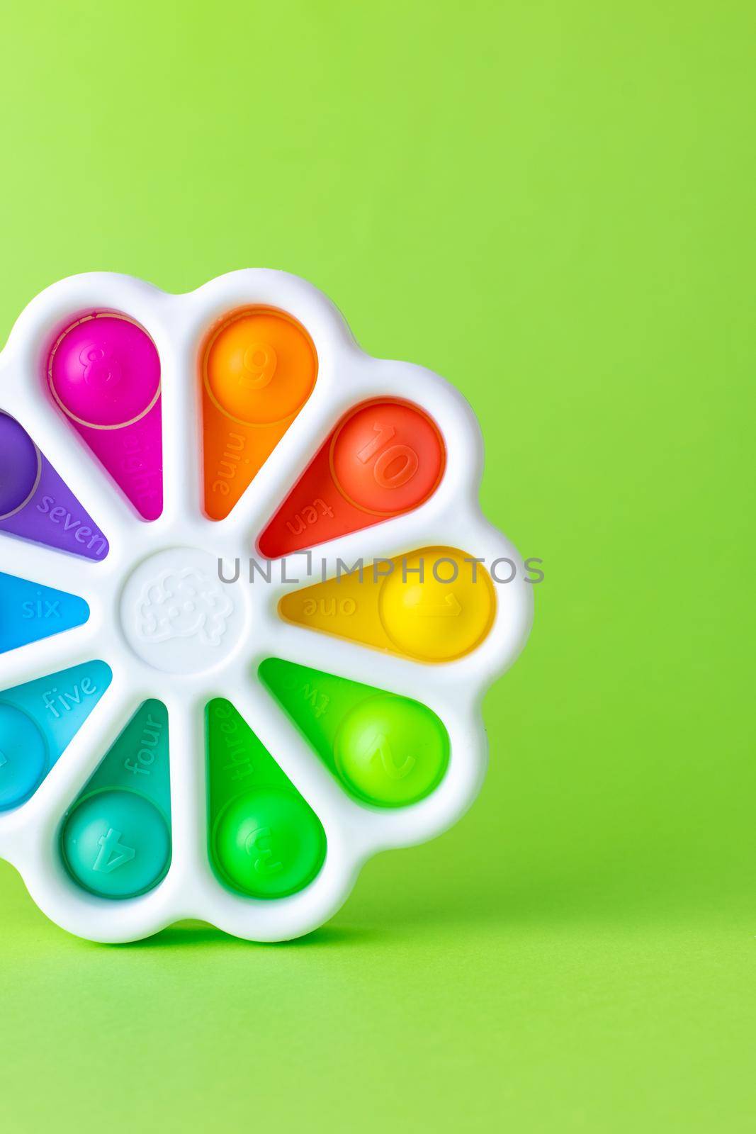 Presses with a finger anti-stress toy pop it on green background. Colorful silicone poppit toy, bubble fidget, simple-dimple by katrinaera