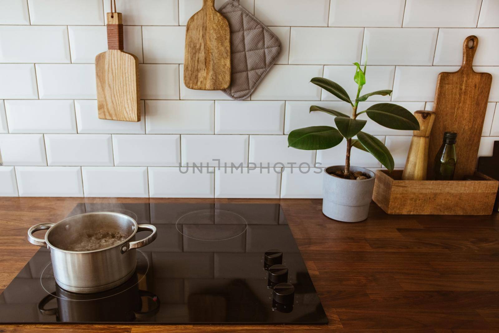 Boiling water in a cooking pot an a pan on a induction stove in the modern white kitchen side view