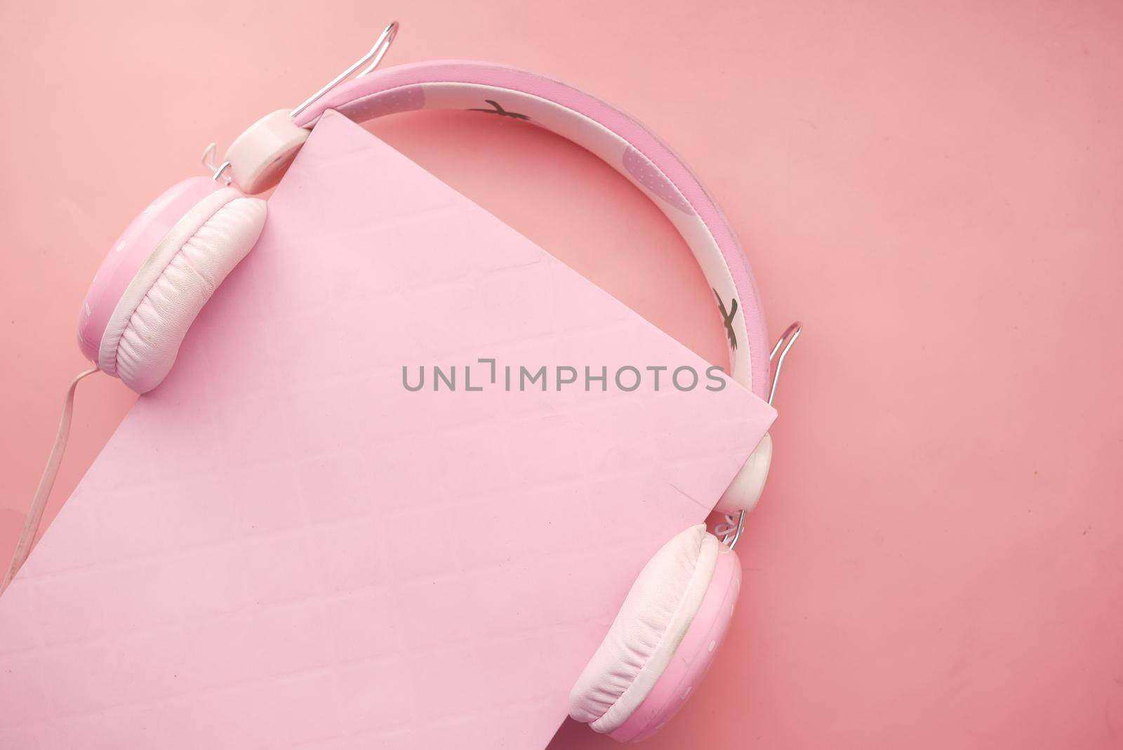 Audio book concept. Headphones and book on pink background
