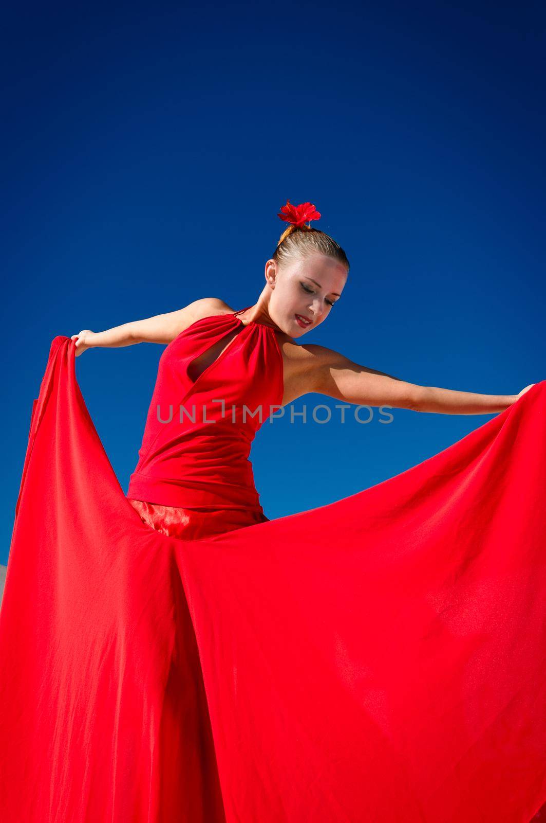 Attractive flamenco dancer wearing traditional red dress with flower in her hair