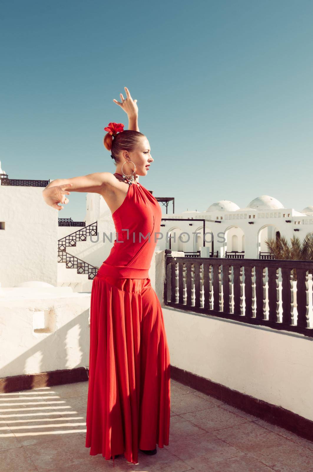 Attractive flamenco dancer wearing traditional red dress with flower in her hair