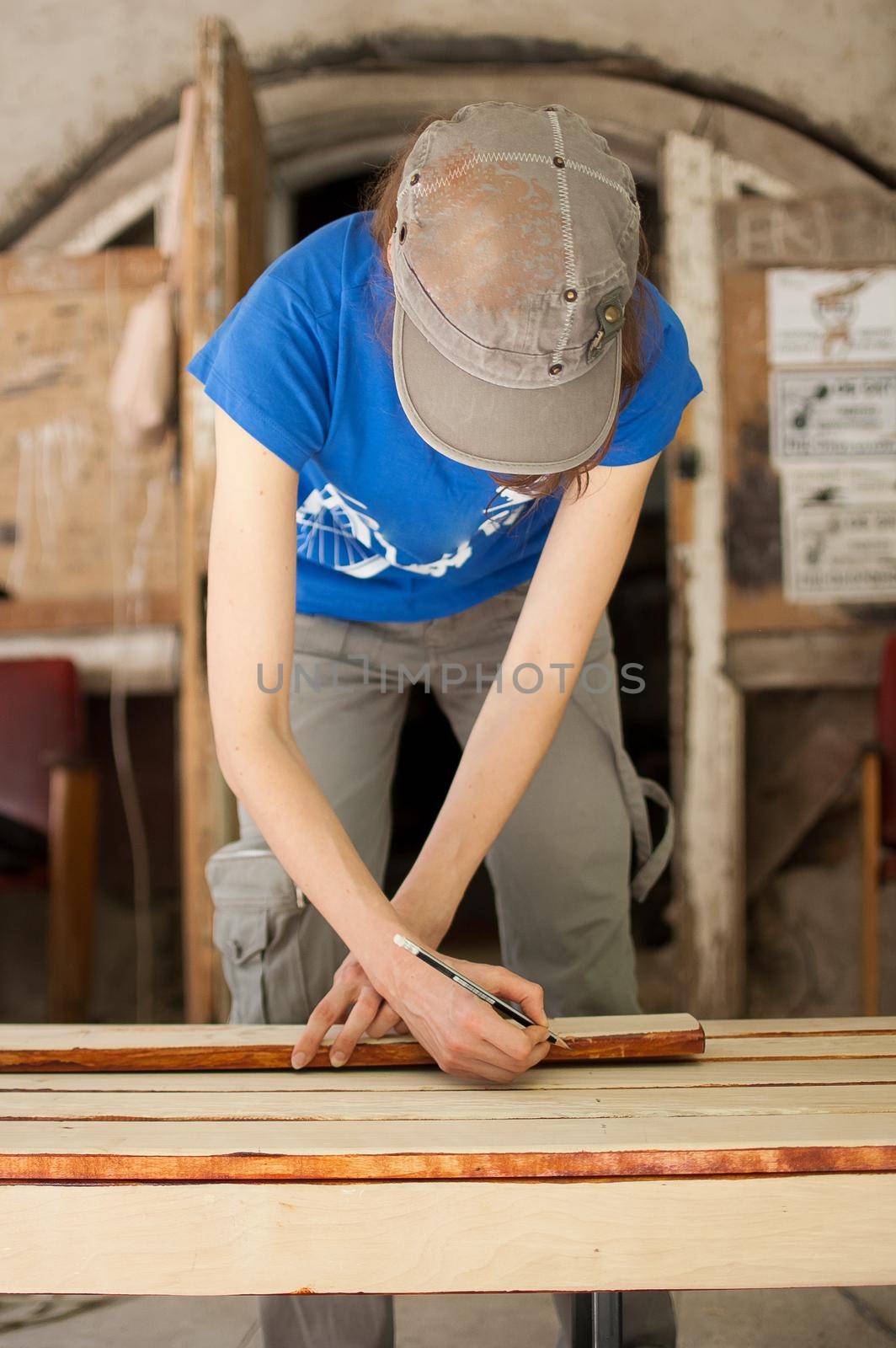 Female hands are making some marks on wooden plank for future holes using pencil for assembling bench, gender equality, feminism, do it yourself concepts. by balinska_lv