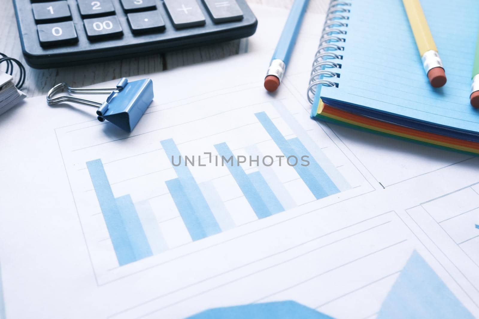 financial graph, calculator and notepad on table.