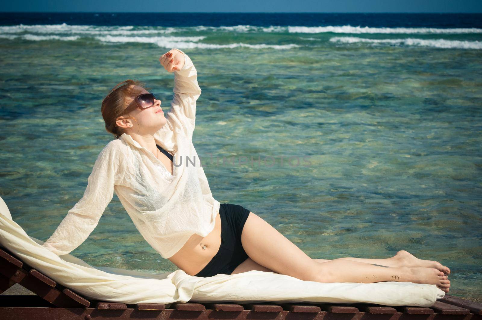 Beautiful young woman lying on a lounge at the beach on a beautiful sunny day