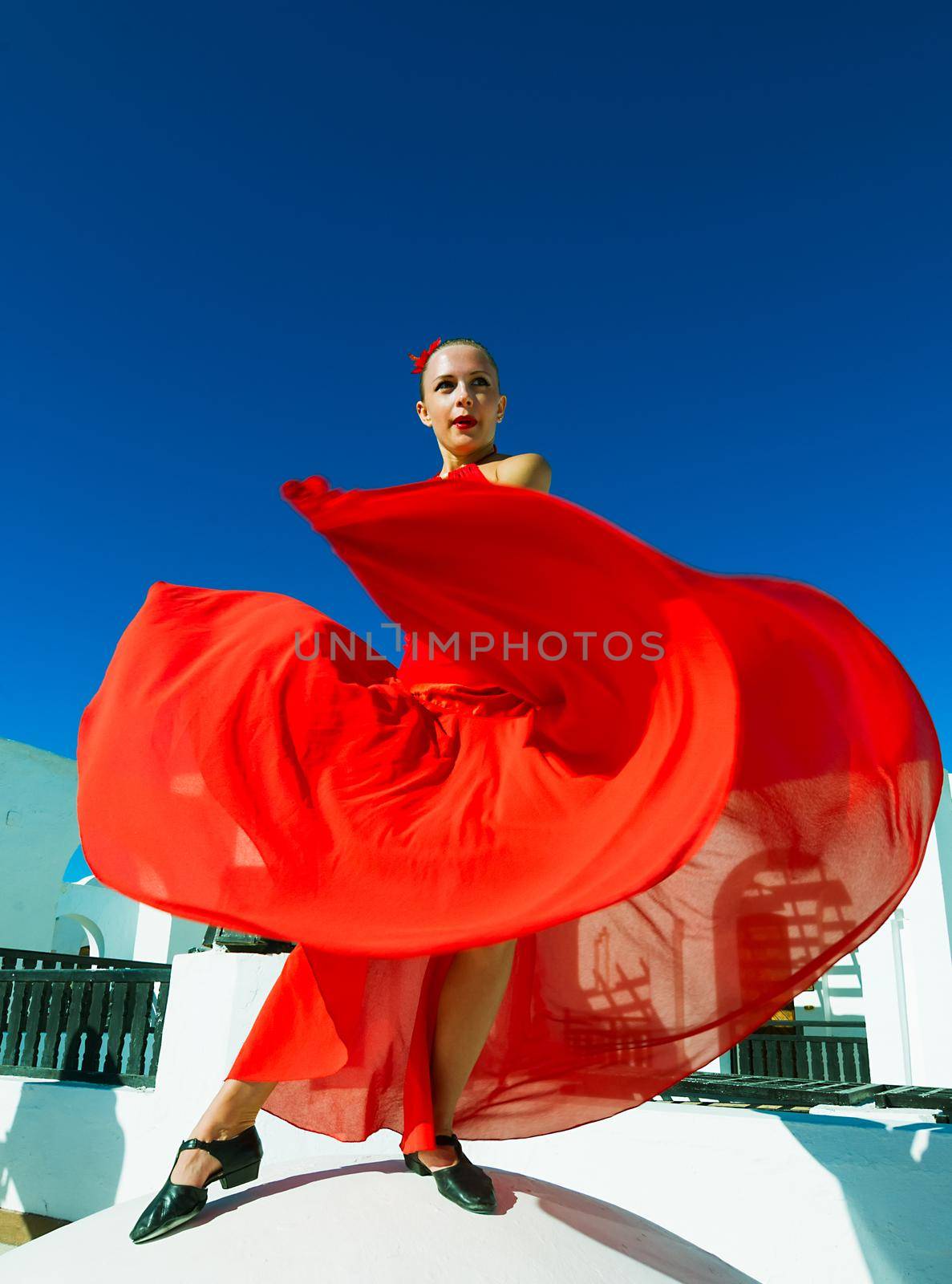 Attractive flamenco dancer wearing traditional red dress with flower in her hair