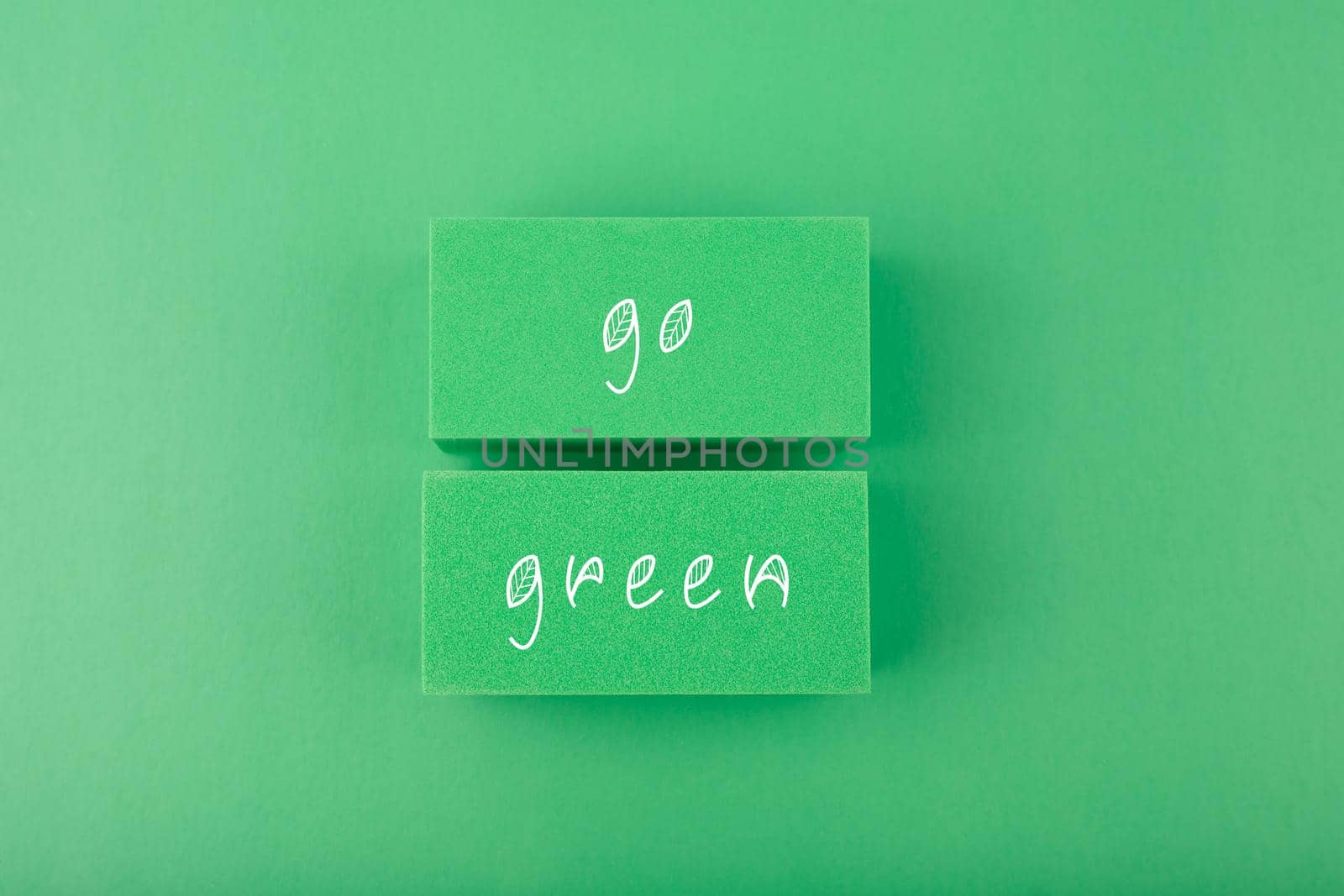 Modern minimal flat lay with go green inscription against light pastel green background. Concept of go green, recycle, reduce, reuse and eco friendly lifestyle