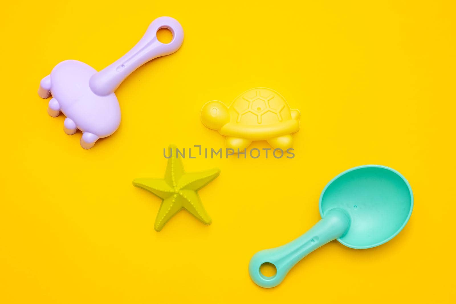 Plastic beach toy pastel color on yellow background. The development of fine motor concept. Creativity Game and summer concept top view