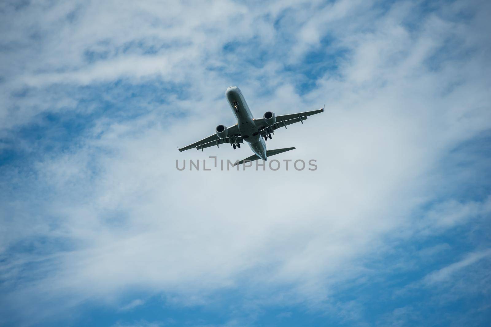 Airplane flying through blue sky with puffy clouds. by jyurinko