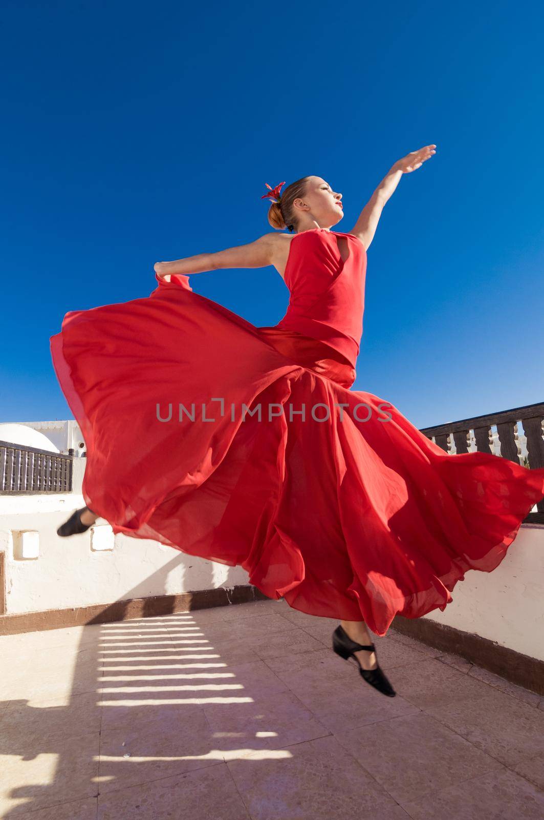Attractive flamenco dancer wearing traditional red dress with flower in her hair