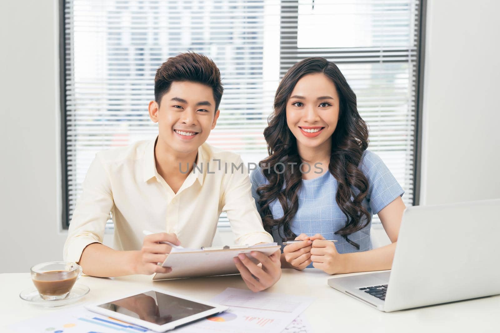 Business people working with computer and doing some paperwork while sitting at desk  by makidotvn