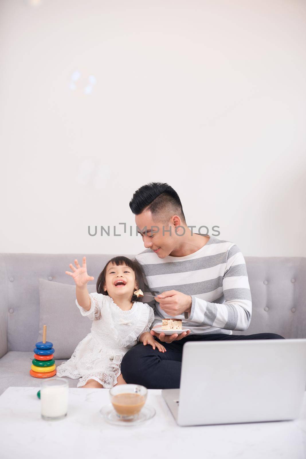 Father and his teenage daughter playing on a portable computer at home. by makidotvn