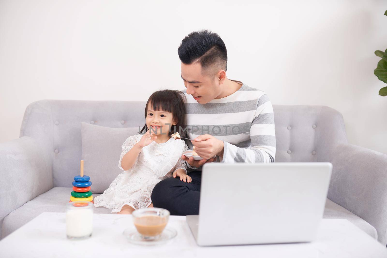 Father and his teenage daughter playing on a portable computer at home. by makidotvn