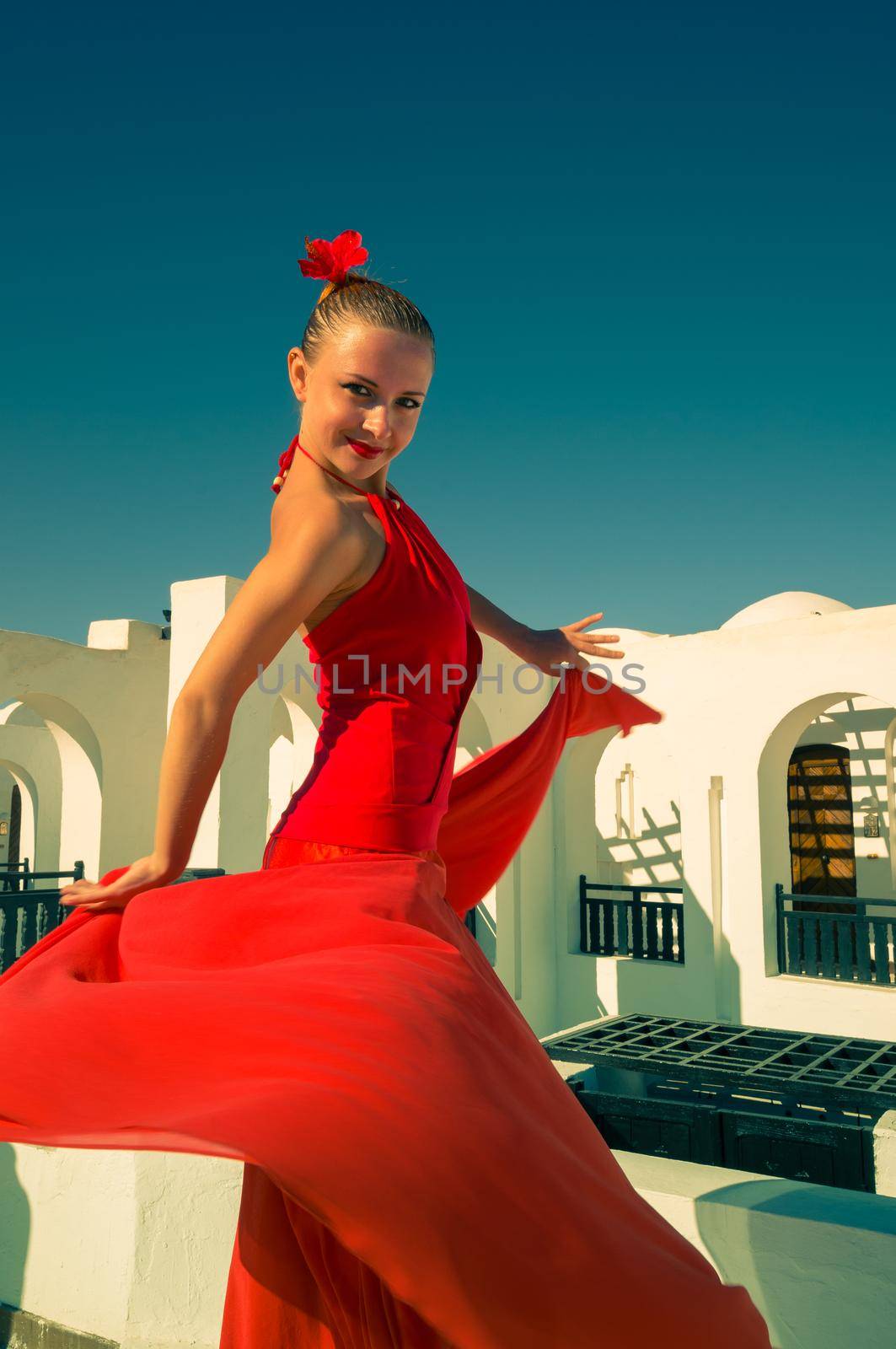 Attractive flamenco dancer wearing traditional red dress with flower in her hair