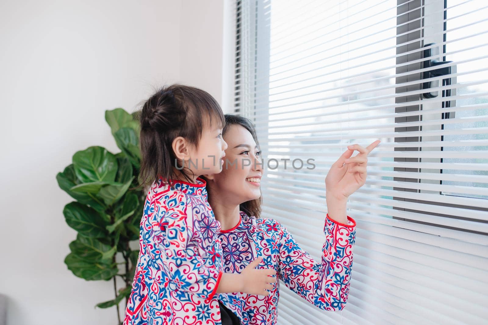 Vietnamese mother and daughter in Ao Dai Traditional dress, celebrate new year at home. Tet Holiday. by makidotvn