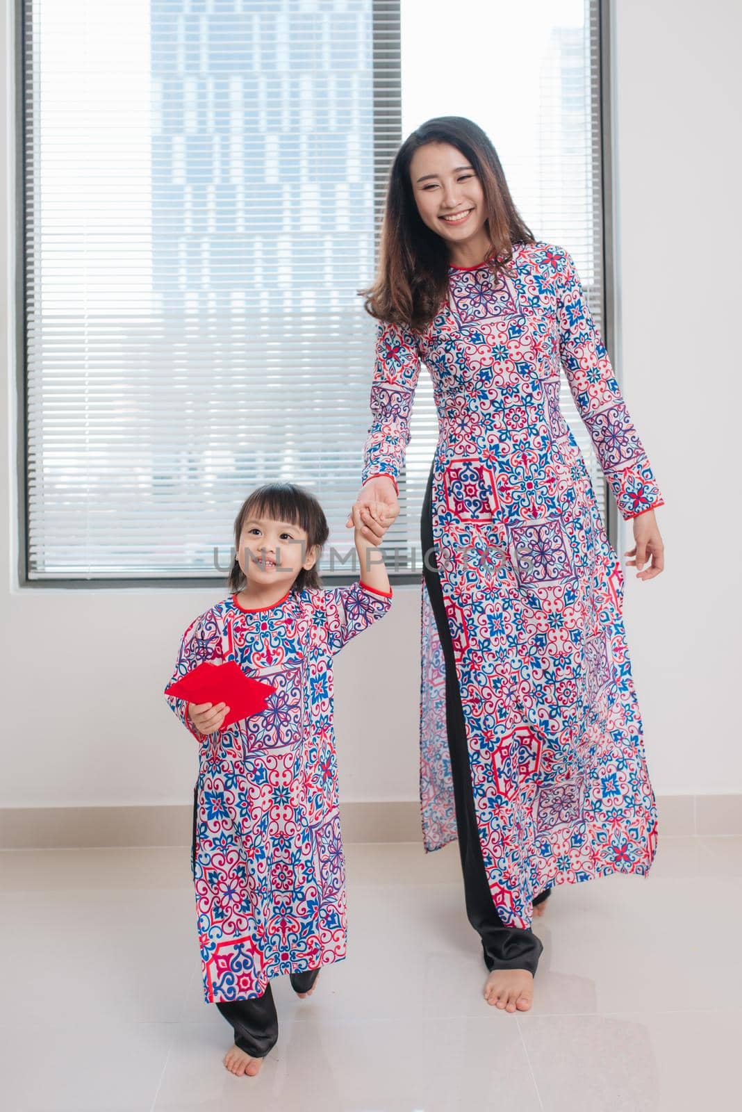 Vietnamese mother and daughter in Ao Dai Traditional dress, celebrate new year at home. Tet Holiday.