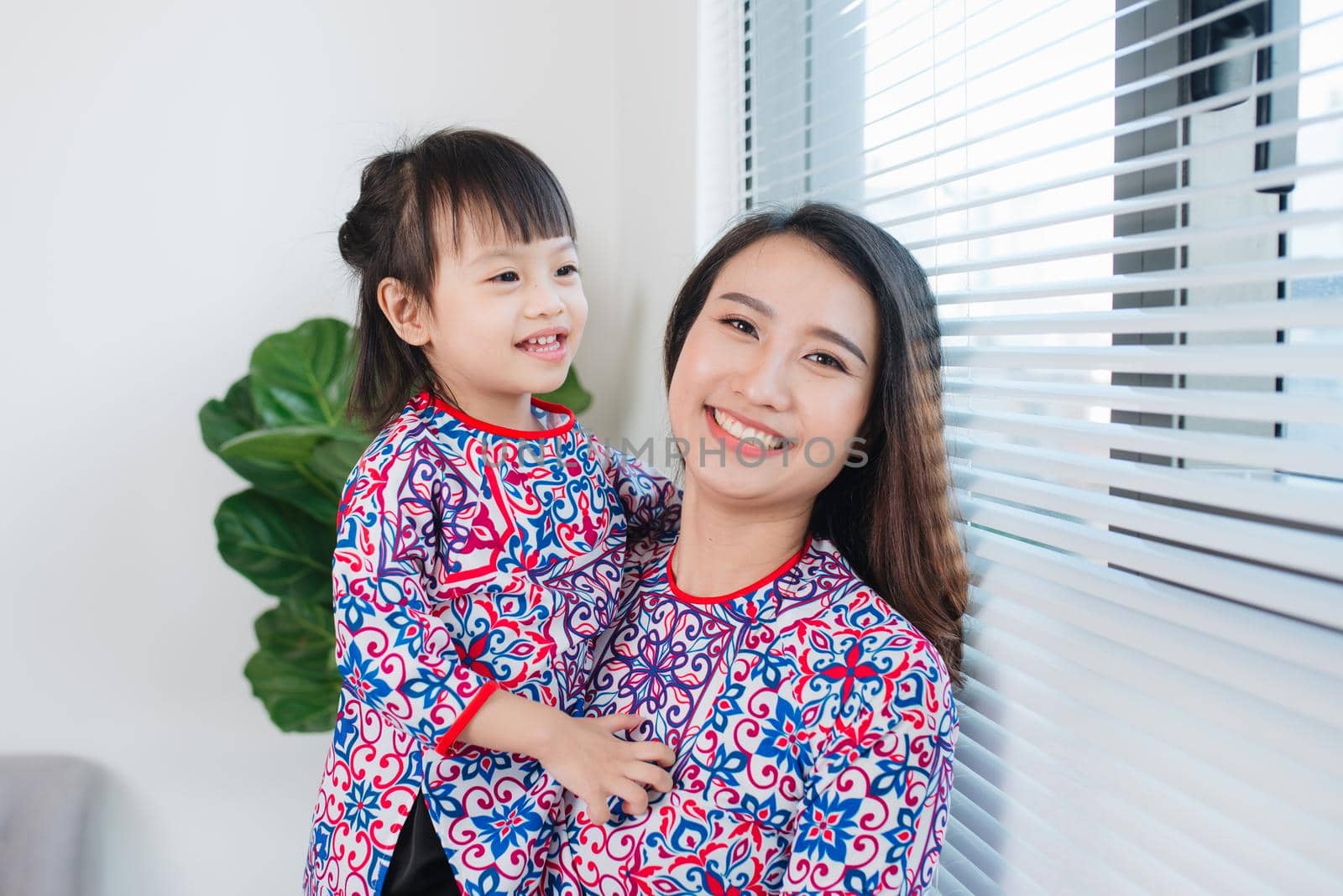 Vietnamese mother and daughter in Ao Dai Traditional dress, celebrate new year at home. Tet Holiday. by makidotvn