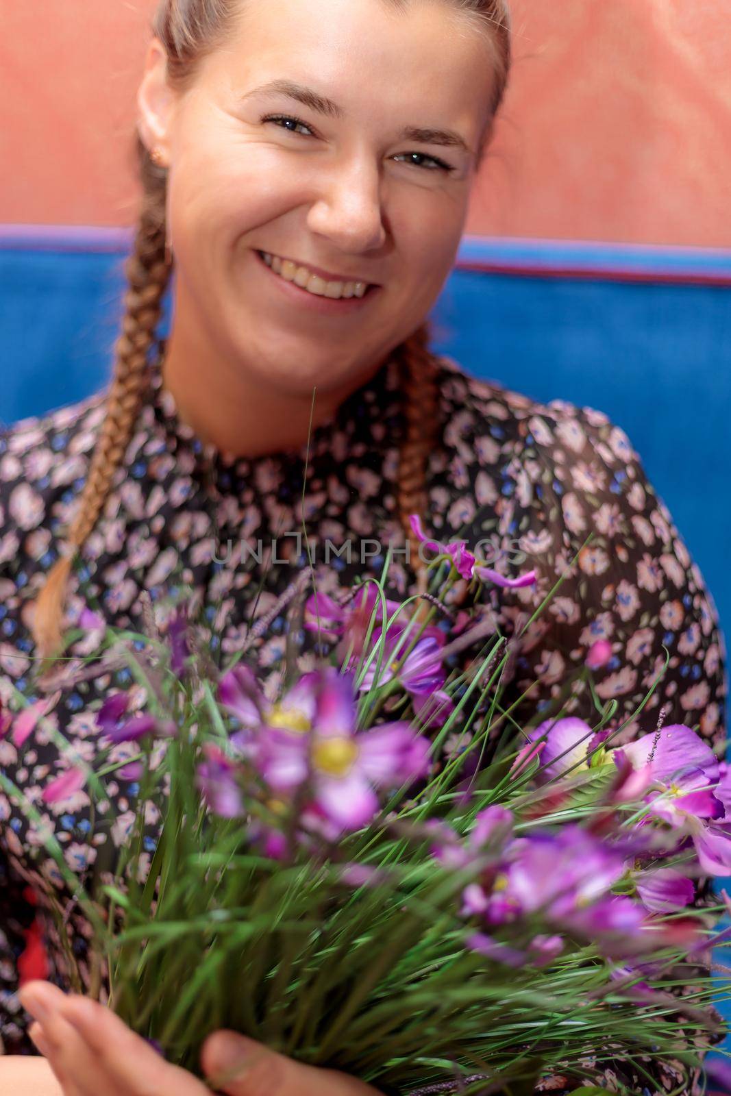 Portrait of a young beautiful girl with a purple bouquet. The girl with pigtails is holding a bouquet of flowers.