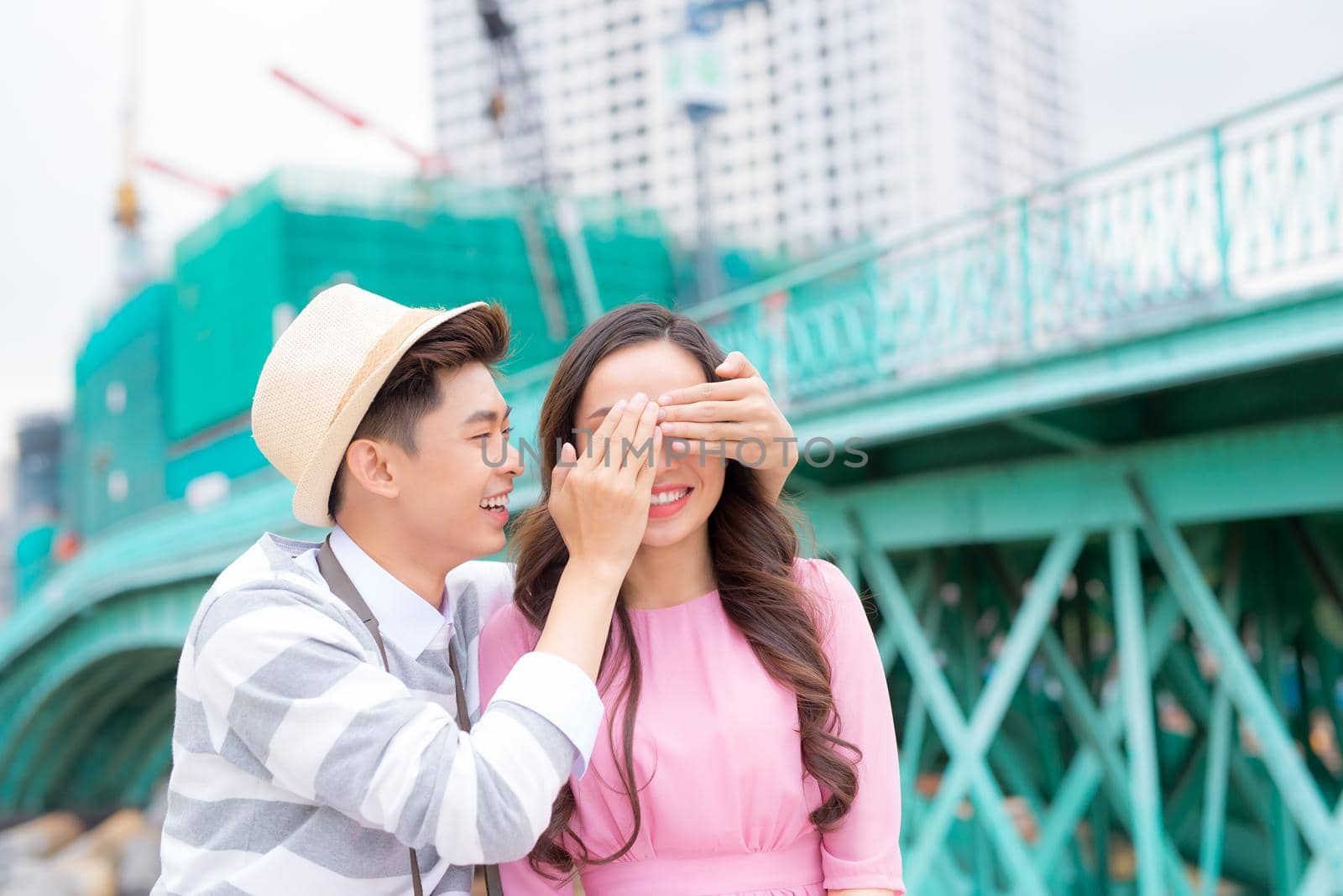 Young man closing his girfriend eyes to make a surprise for her - Love, holiday and people concept