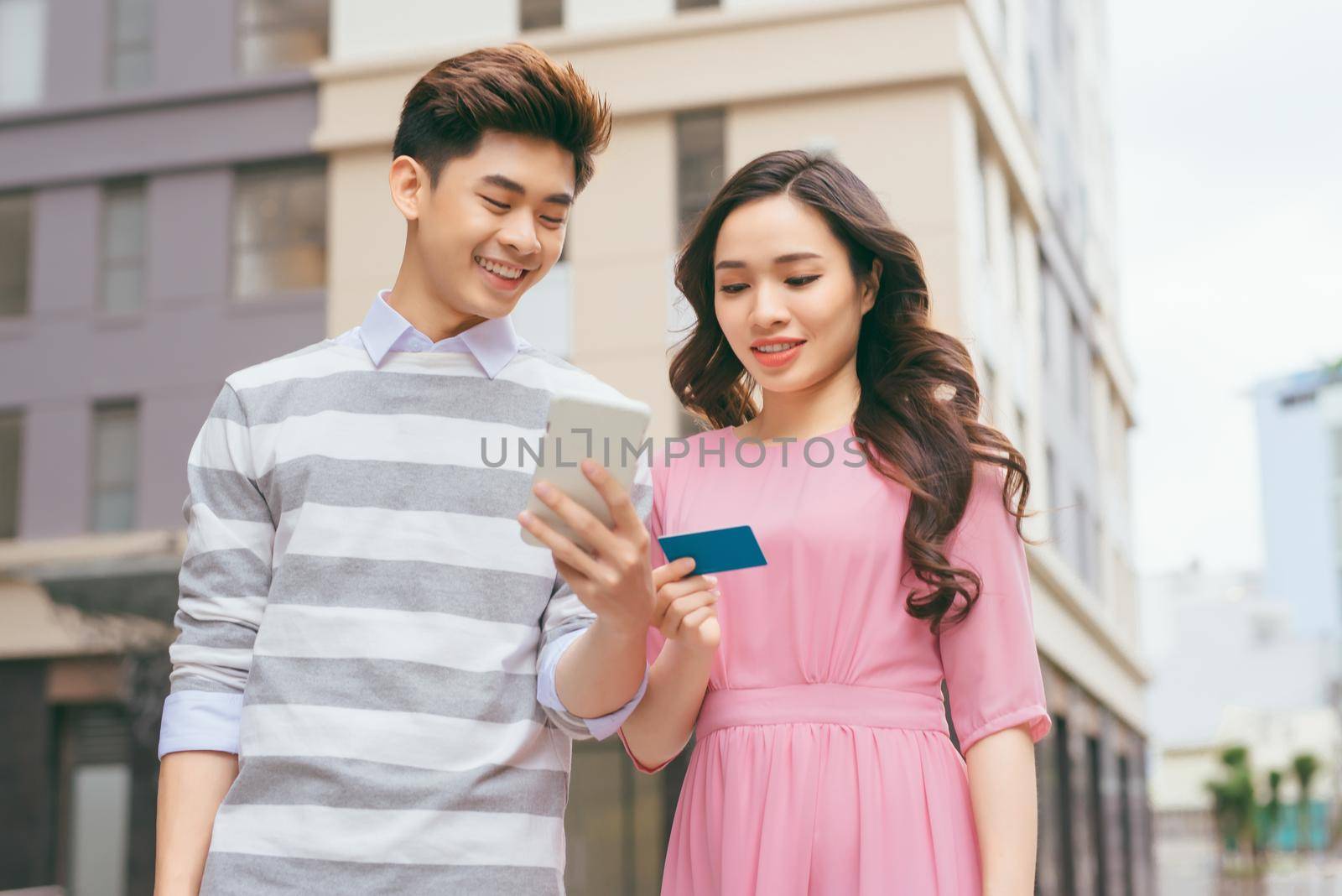 Beautiful asian couple shopping with a credit card in the city