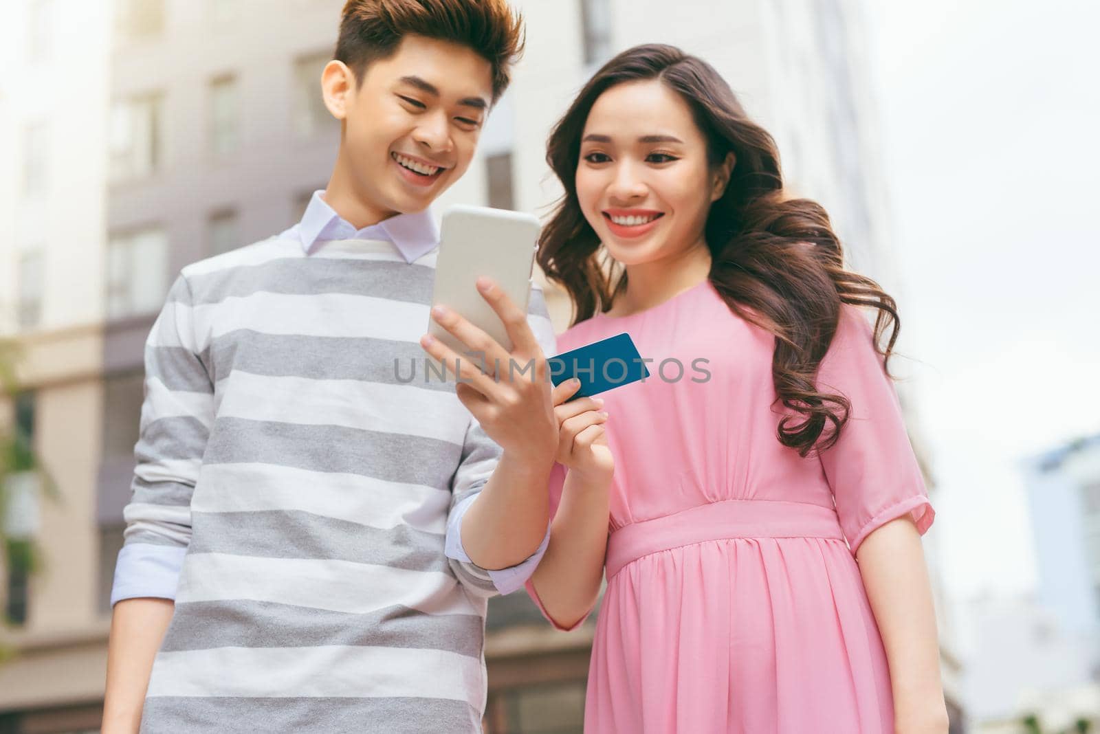 Beautiful asian couple shopping with a credit card in the city