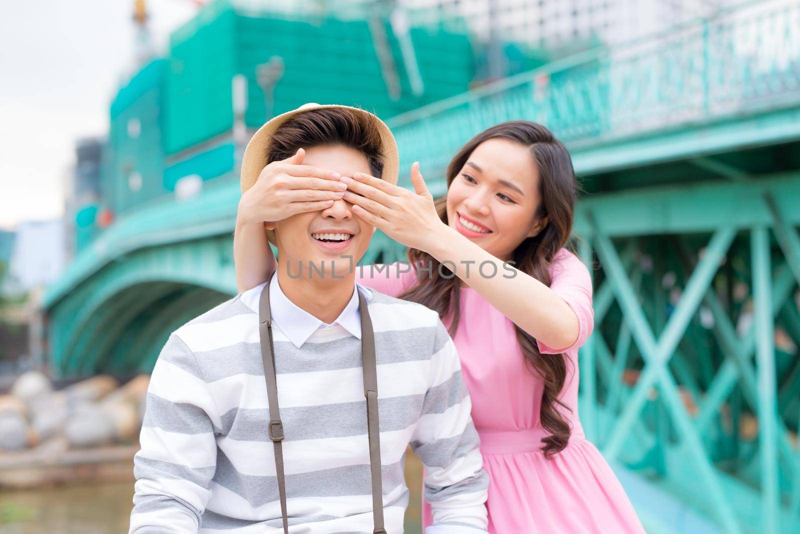 Young man closing his girfriend eyes to make a surprise for her - Love, holiday and people concept