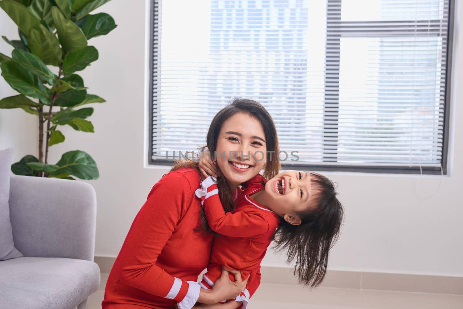 Portrait of beautiful young mother and her daughter hugging, looking at camera and smiling by makidotvn