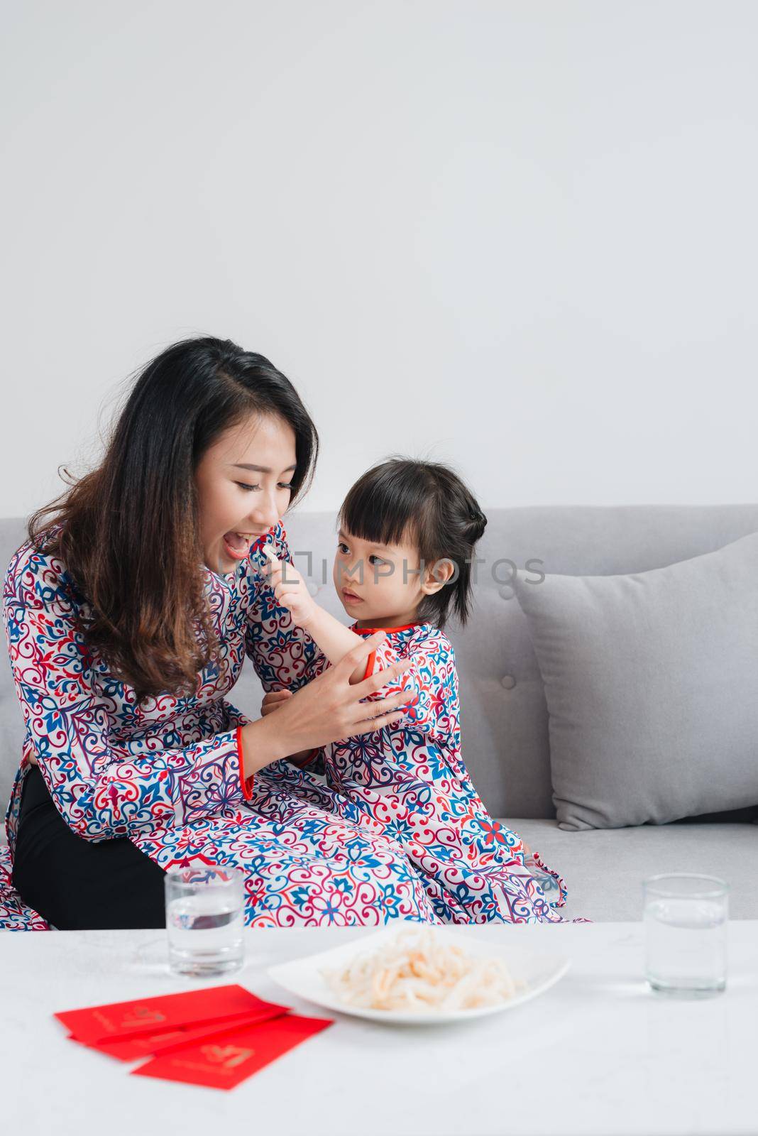 Vietnamese mother and daughter in Ao Dai Traditional dress, celebrate new year at home. Tet Holiday.