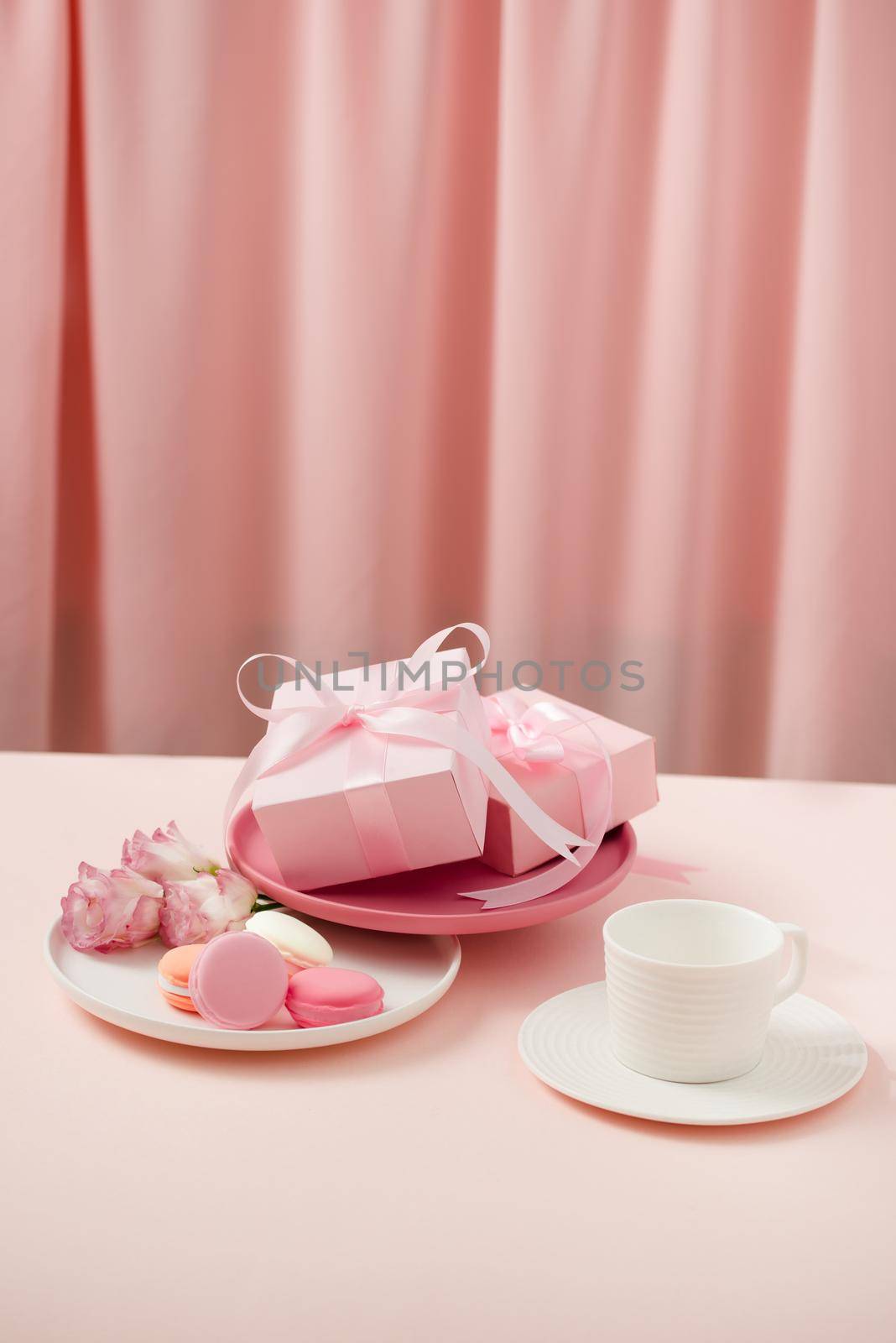 Happy woman/mother"s Day image of a coffee or tea cup and lisianthus flower with macaroon and gifts beside on drapes of pink.  by makidotvn