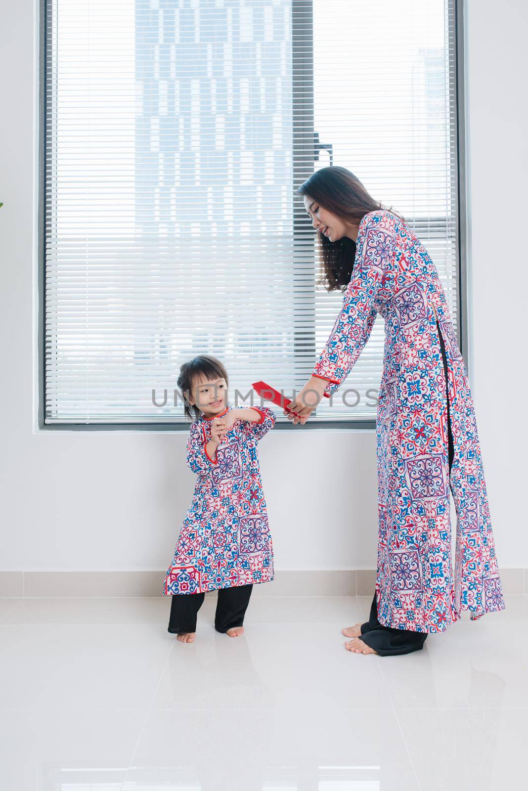 Vietnamese mother and daughter in Ao Dai Traditional dress, celebrate new year at home. Tet Holiday.