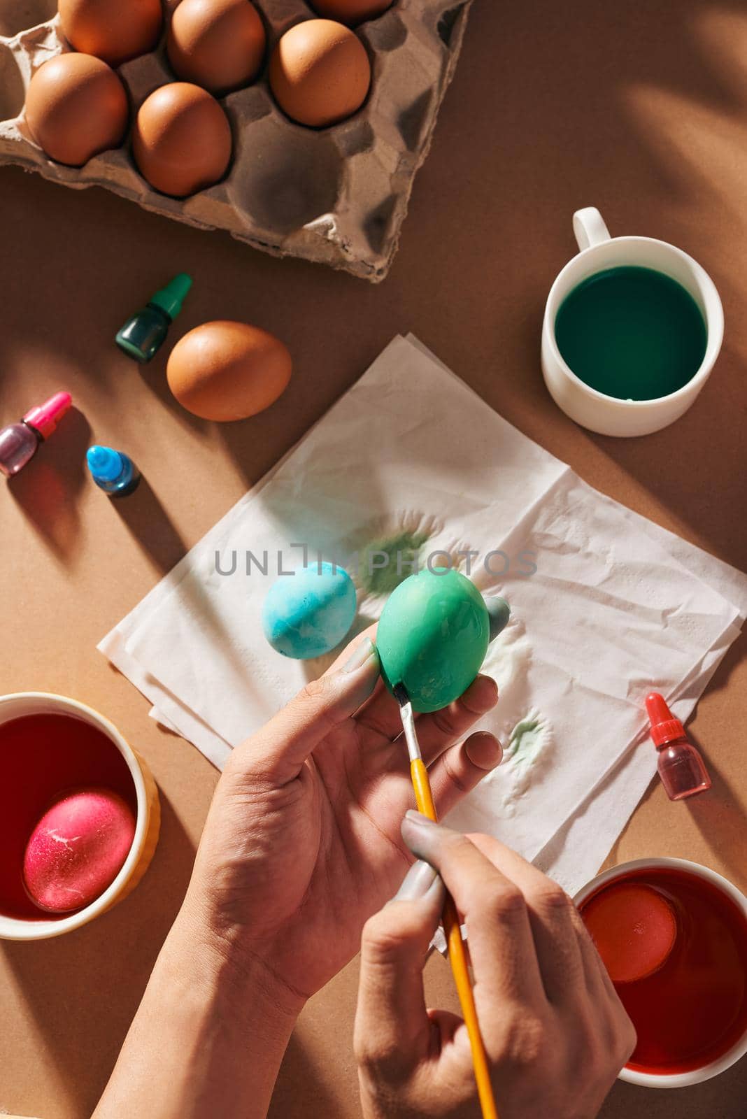 Holidays, tradition and people concept - close up of man hands coloring easter eggs with brush