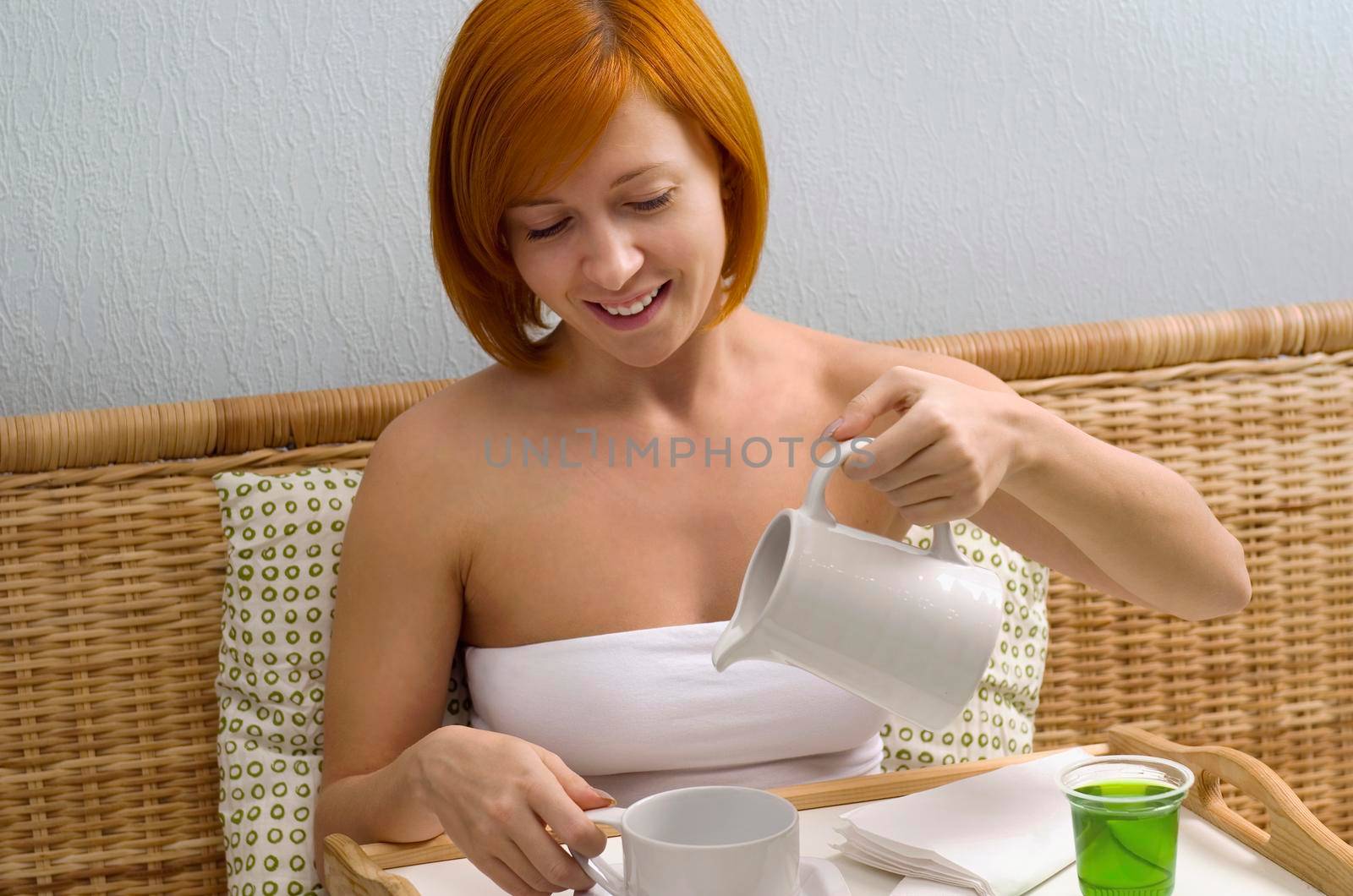 Young red woman in bed having breakfast