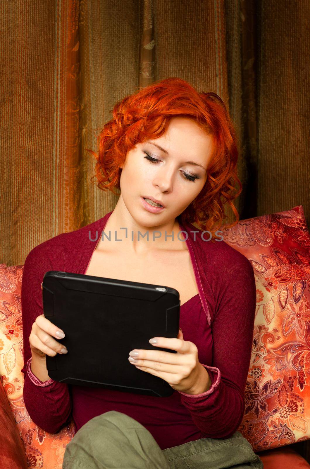 Young woman on a couch interacting with tablet pc or e-reader