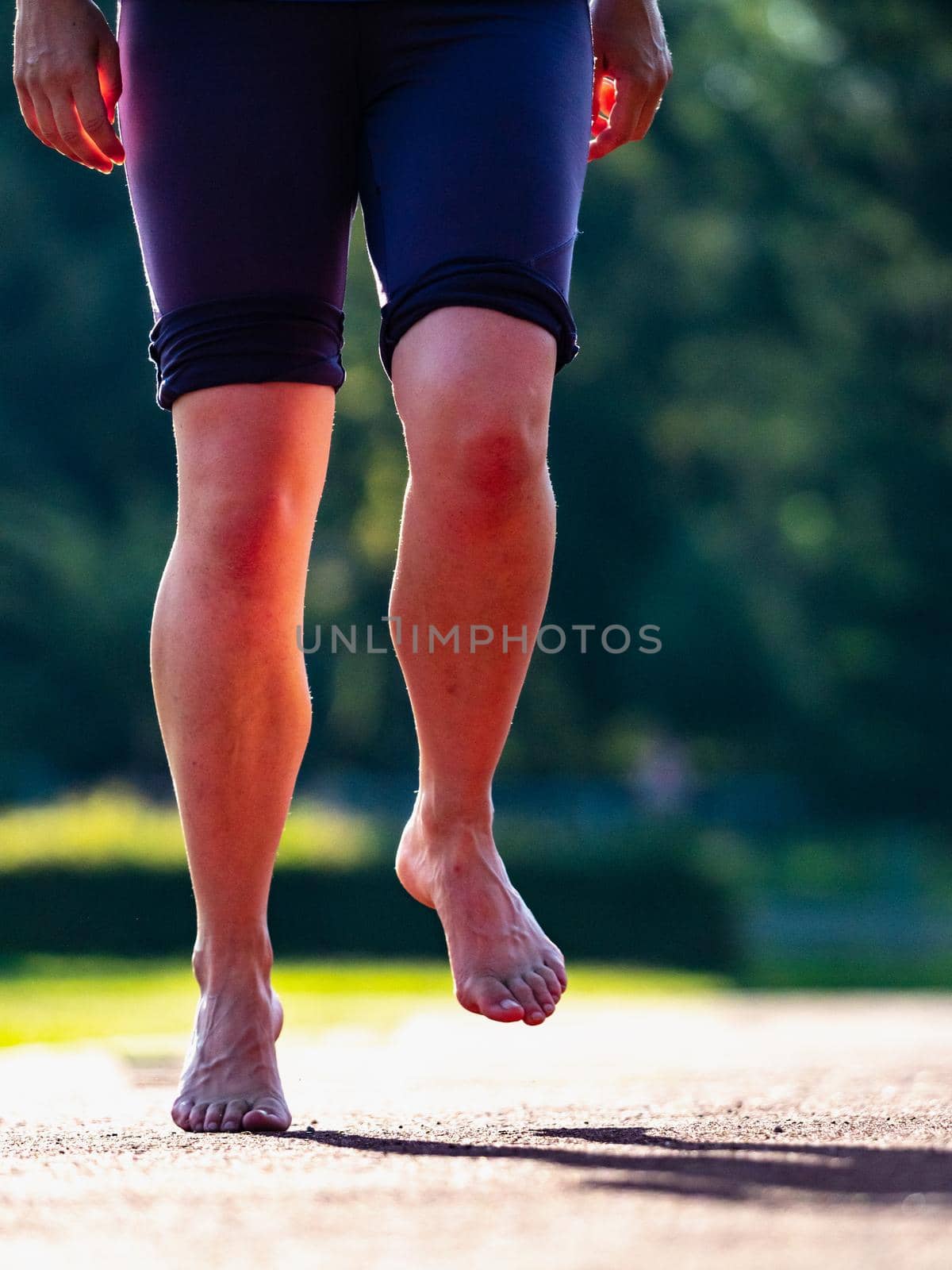 Solid bare feet of a hard training woman. A woman runs along the soft surface of a running track in short leggings.