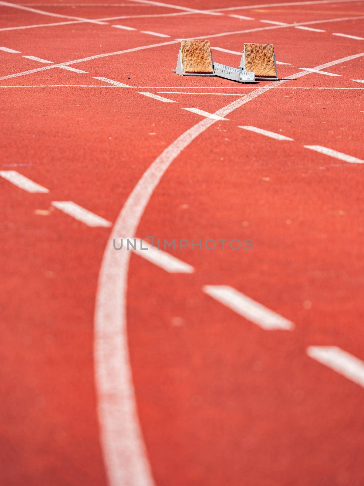 Empty starrting blocks at cindertrack of athletics stadium. Runner tracks painted on red tamrac
