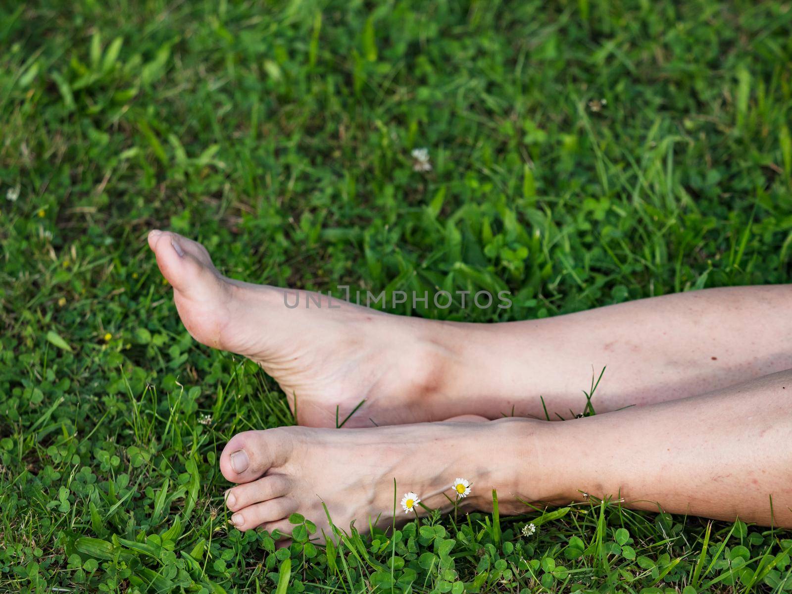 Tired female legs with bare feet on the green grass. Mature woman by rdonar2