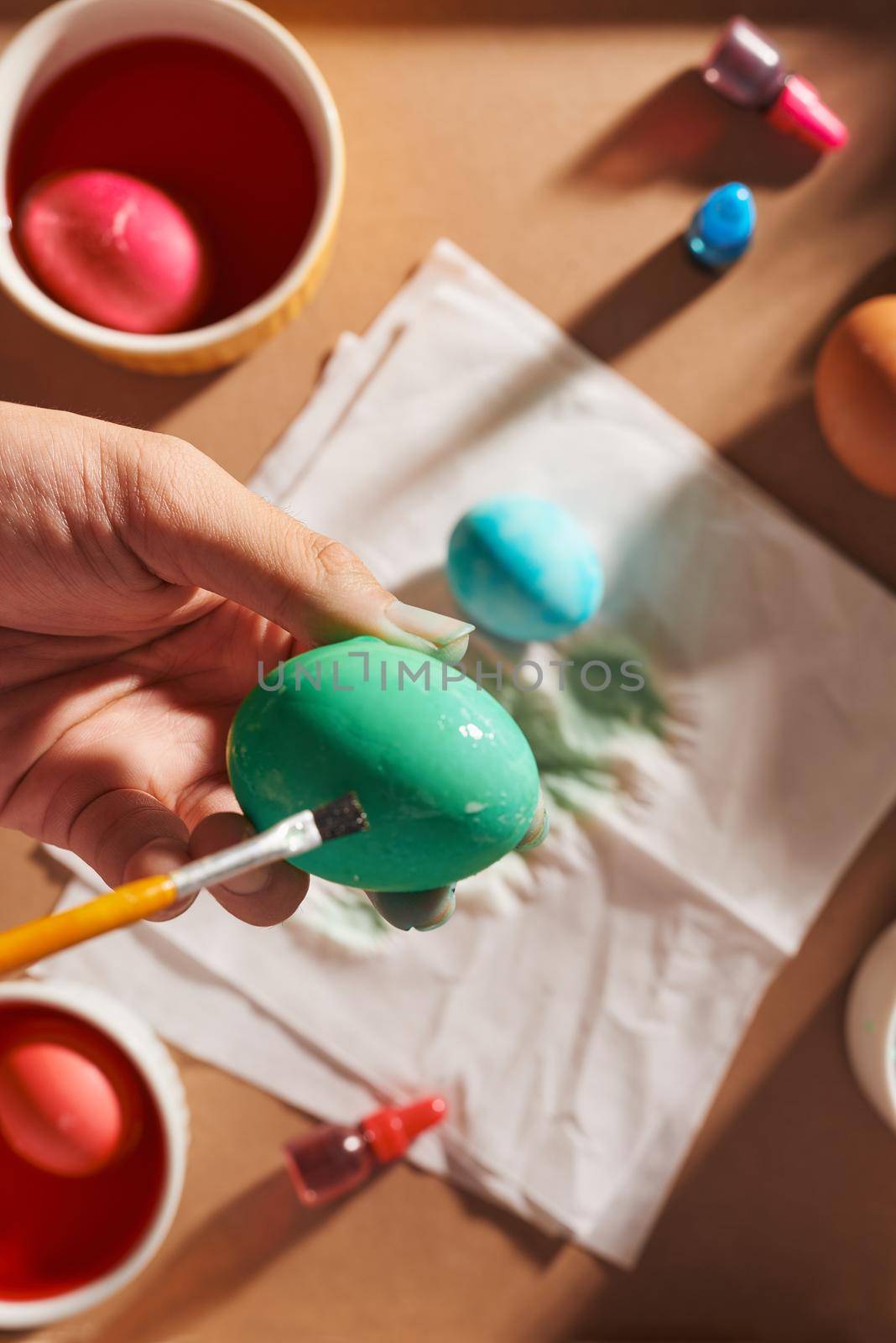 Holidays, tradition and people concept - close up of man hands coloring easter eggs with brush by makidotvn