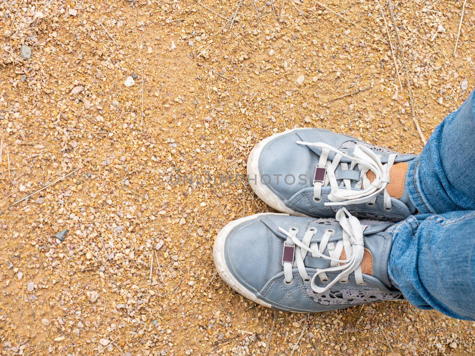 Close-up of girl's legs in denim sneakers and tight slim fit denim pants. Walk through the park on foot.