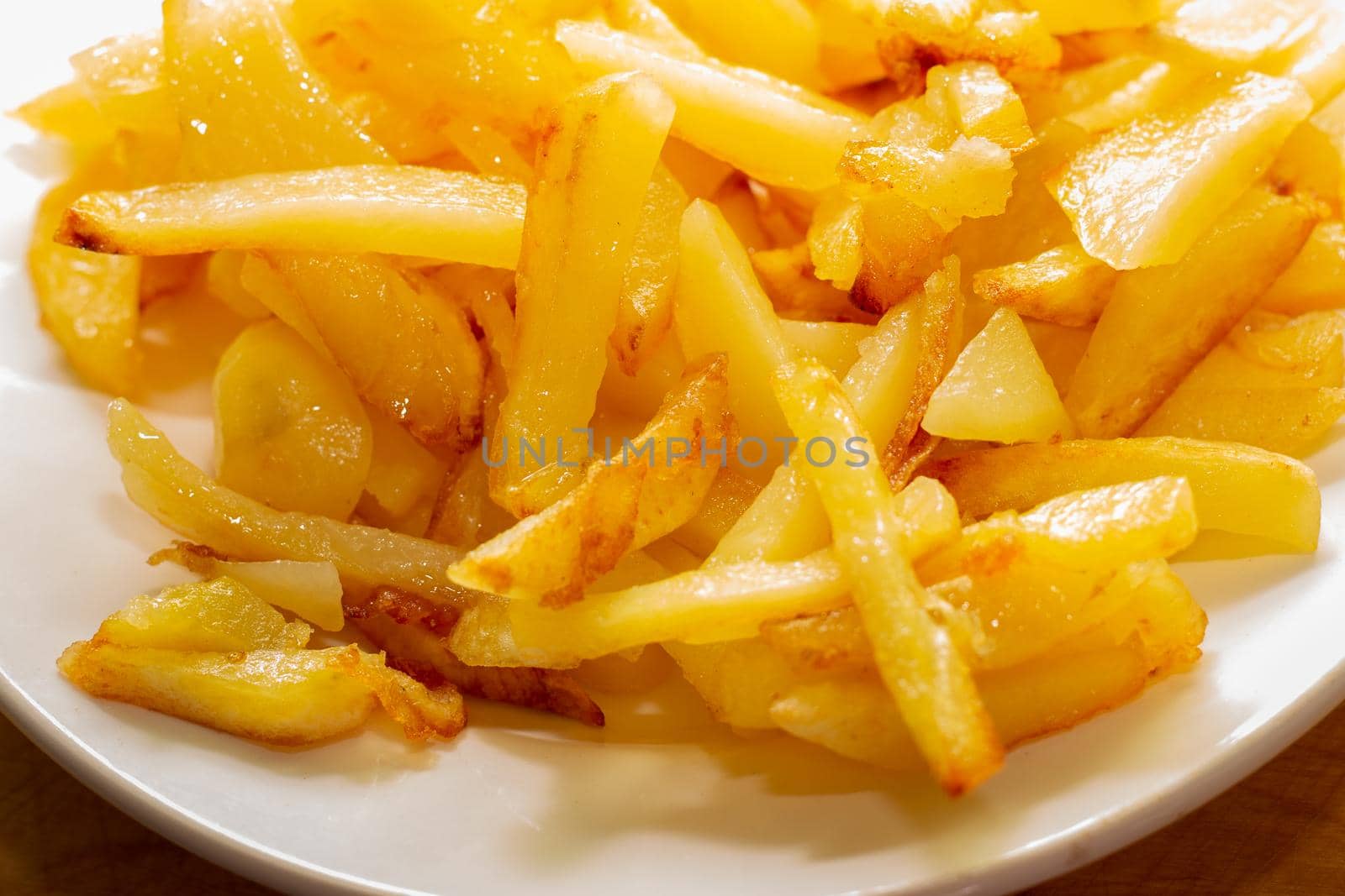 Fresh golden fried potatoes on a white plate, close-up. Delicious vegetable dish.