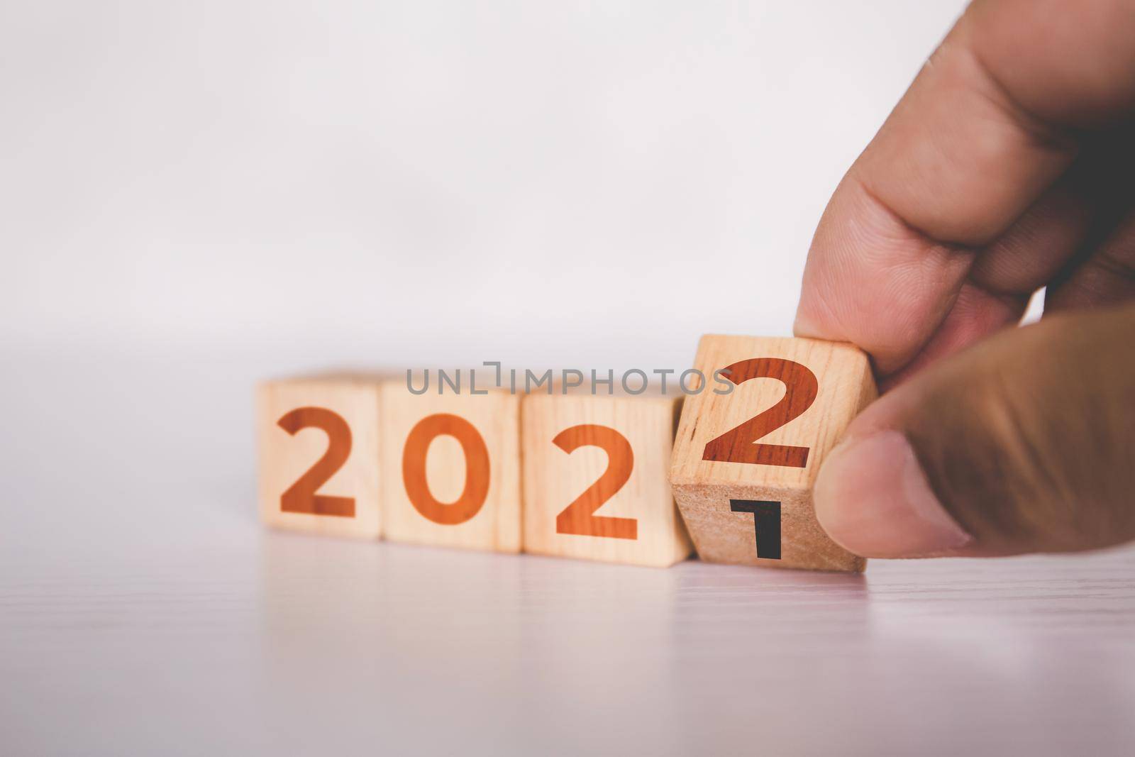 Hands flipping cube wooden block with text year 2022, beginning and trend, calendar and time, determination target and planning for achievement, motivation and aspirations, business concepts. by nnudoo