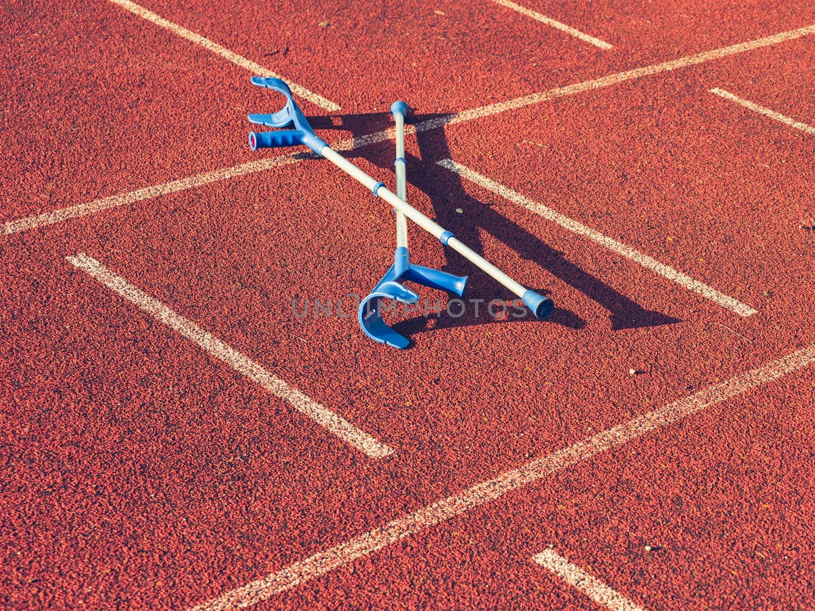 Pair of hospital crutches on stadium running track. Sticks for help when you have an orthopedic injury and are giving it time to heal