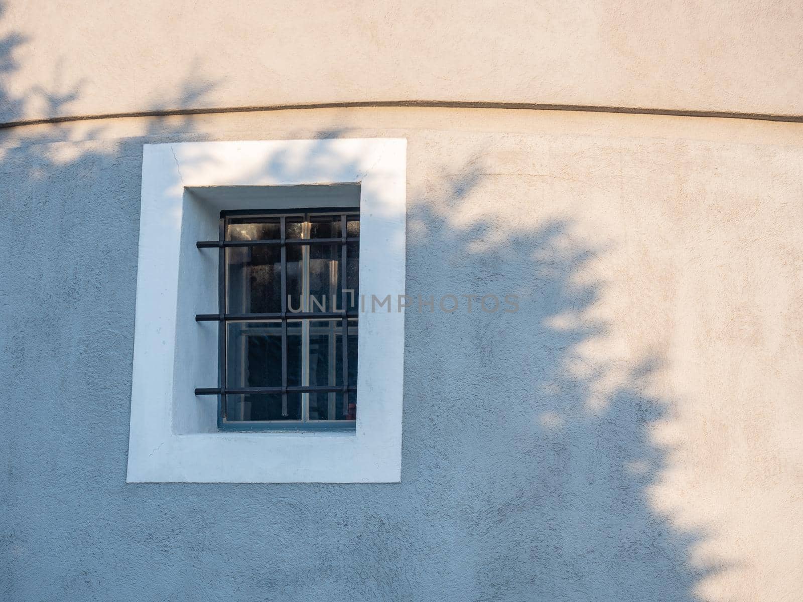 Window with iron bars on the wall of the old fort. Historical windmill  by rdonar2