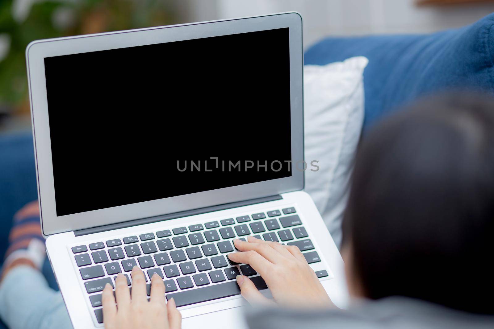 Young asian woman work from home with laptop computer blank screen mockup, freelance girl using notebook with empty, girl typing keyboard and relax with multimedia, business and communication concept.