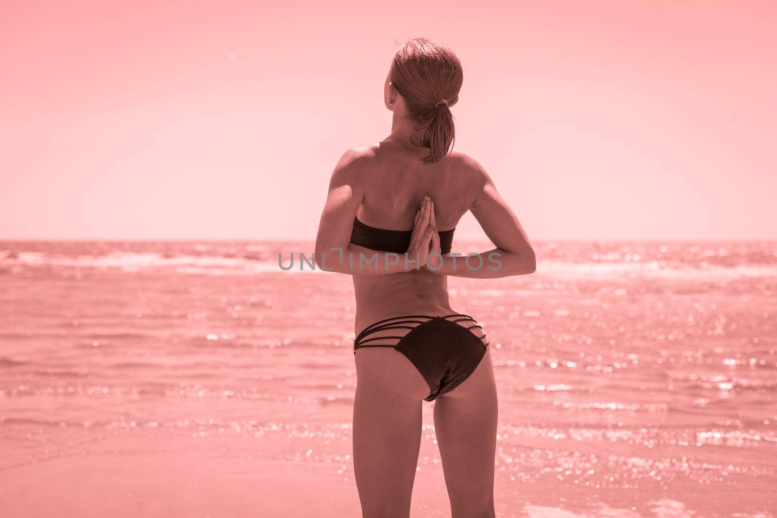 Woman doing yoga asana reverse namaste at the beach