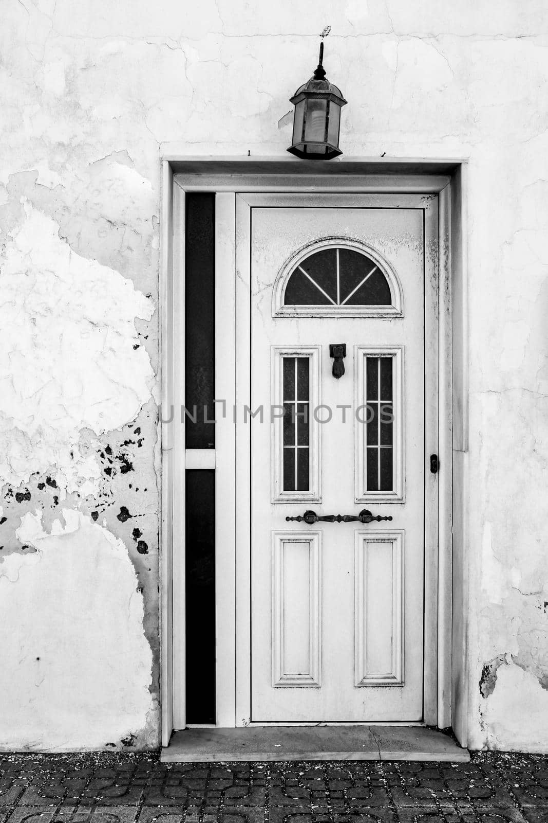 Typical Andalusian whitewashed facade with white metal door and vintage lantern