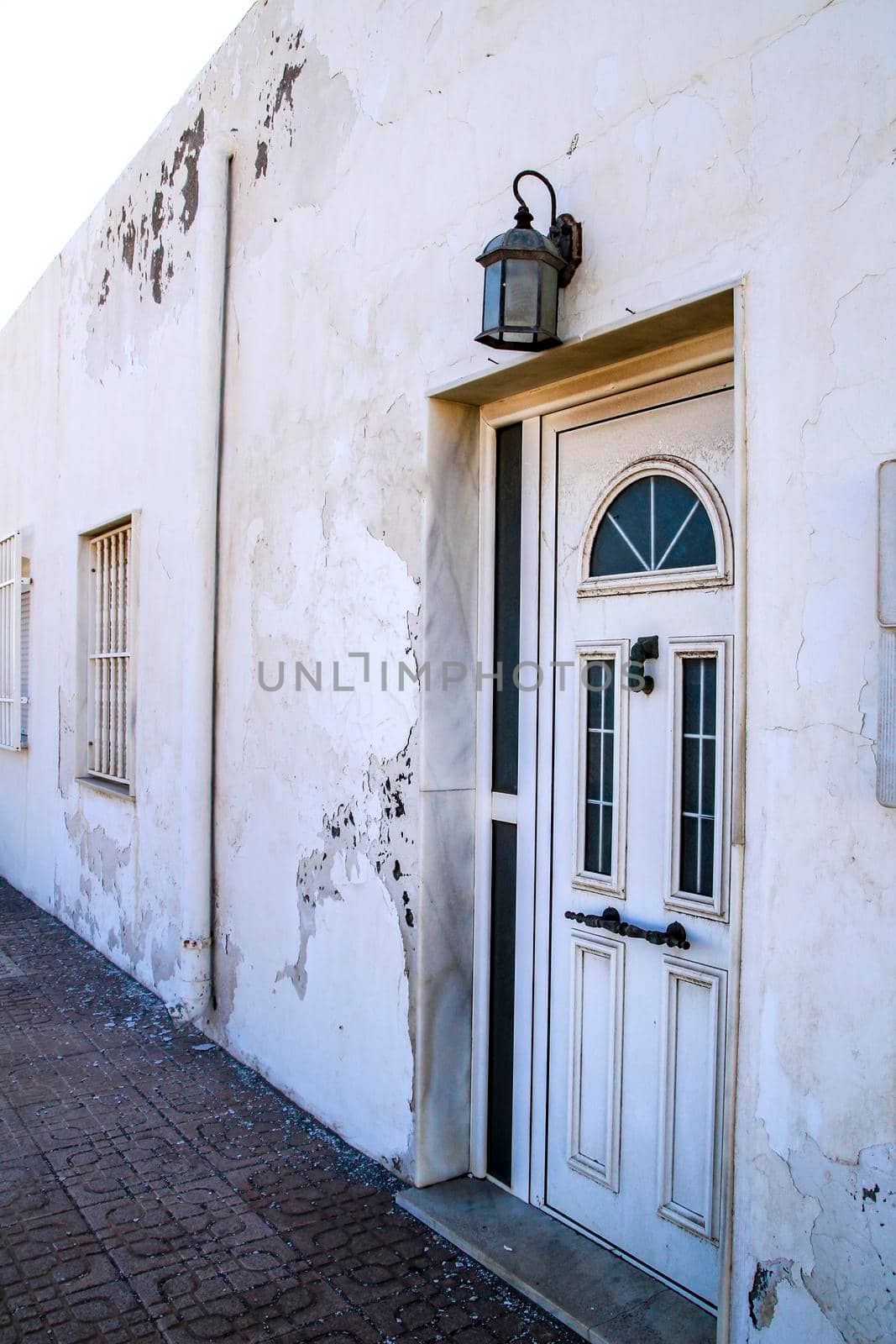Typical Andalusian whitewashed facade with white metal door and vintage lantern